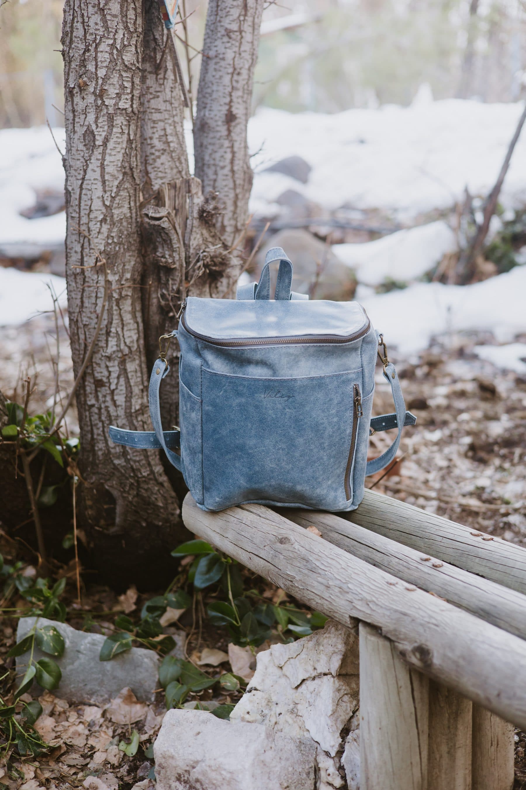 Mochila Valiz apoyada en un pasamanos de madera, bosque con nieve